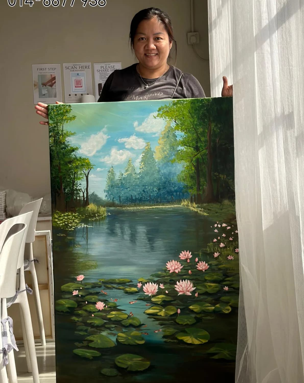 Student holding large water lily landscape painting in Rycca studio